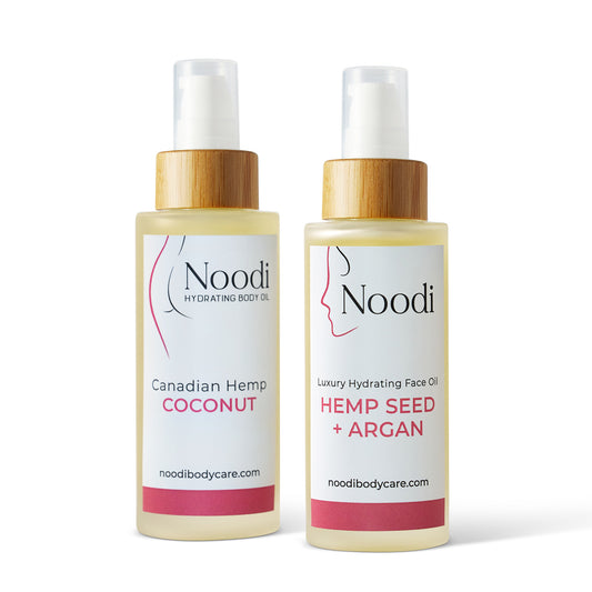 Two Noodi hydrating oil bottles, one labeled "Canadian Hemp Coconut" and the other "Luxury Hydrating Face Oil: Hemp Seed + Argan."